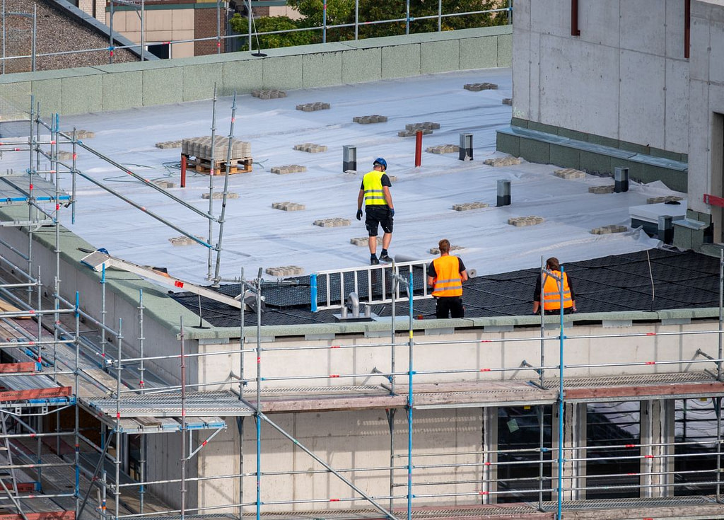 flat roof replacement cost workers installing new roof