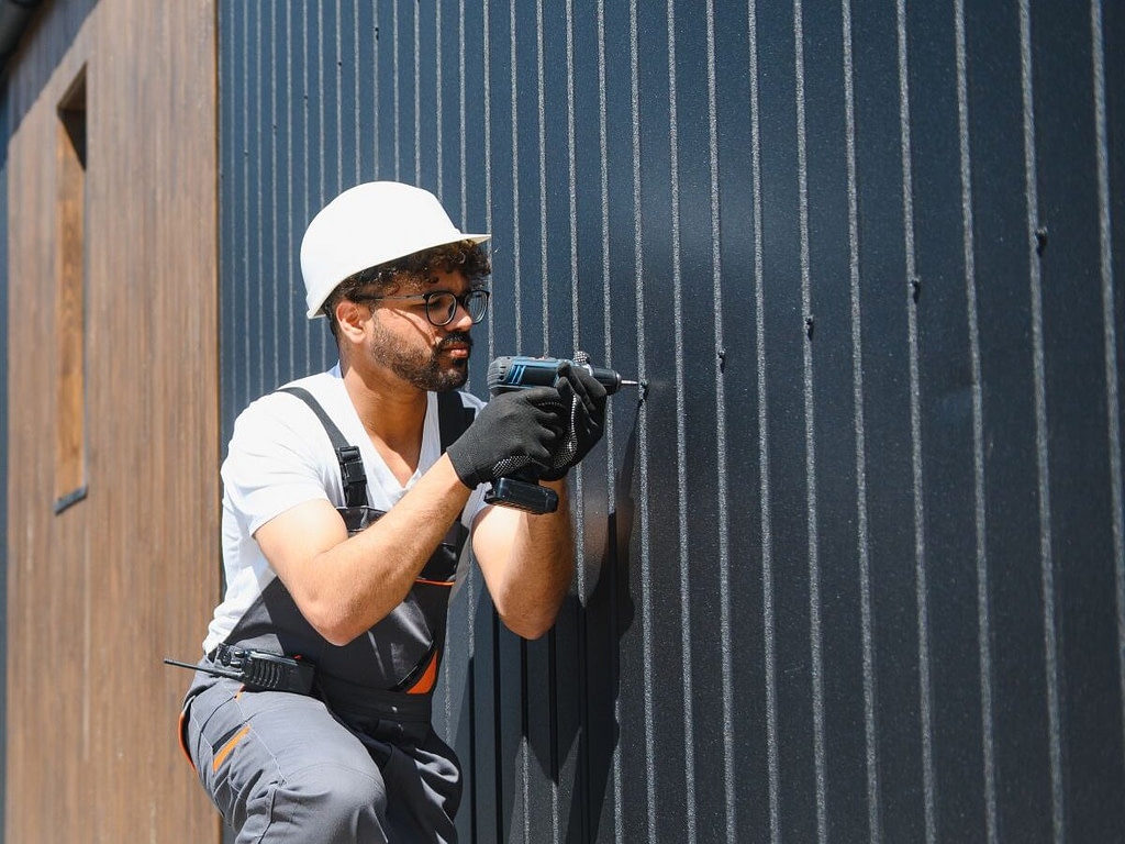 best siding for albert lea mn homes worker using drill to install metallic siding