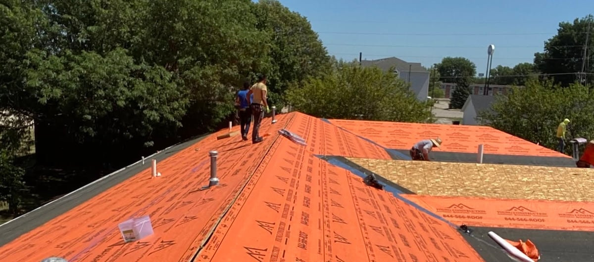 Workers installing roofing materials outdoors
