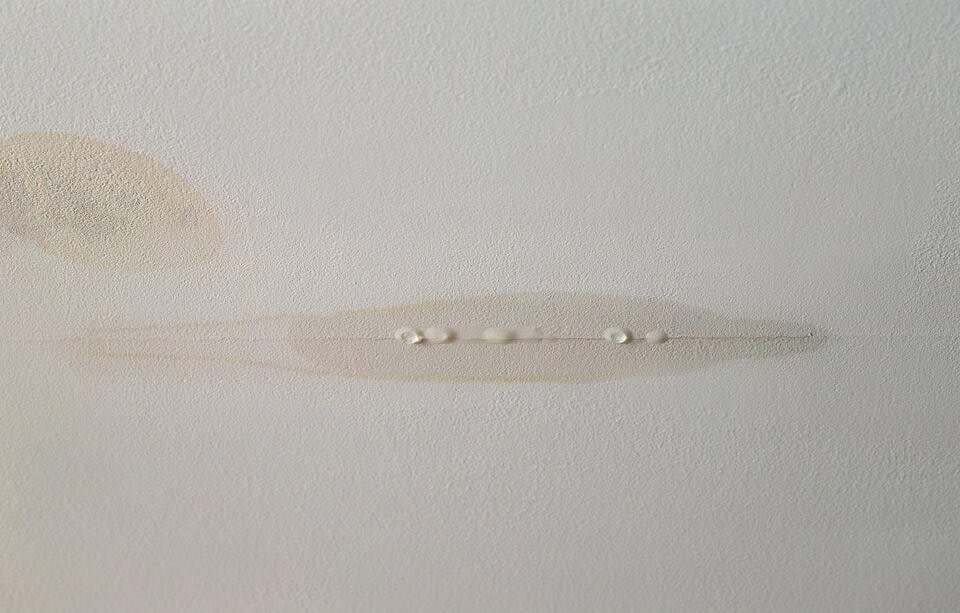 water leaking from ceiling-close up of water coming out of ceiling material