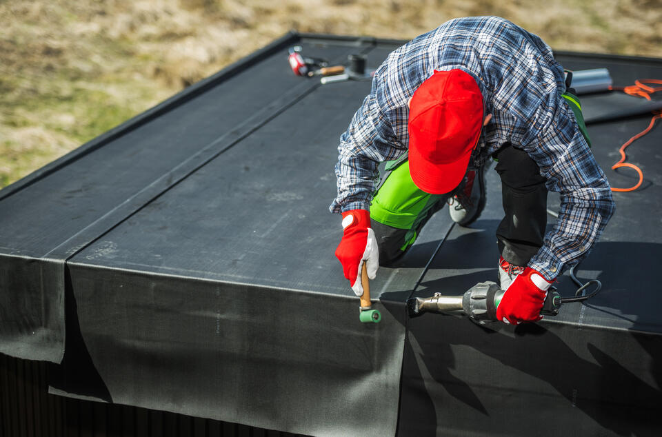 epdm roofing-tech using torch to install a panel of epdm roofing materials to flat roof