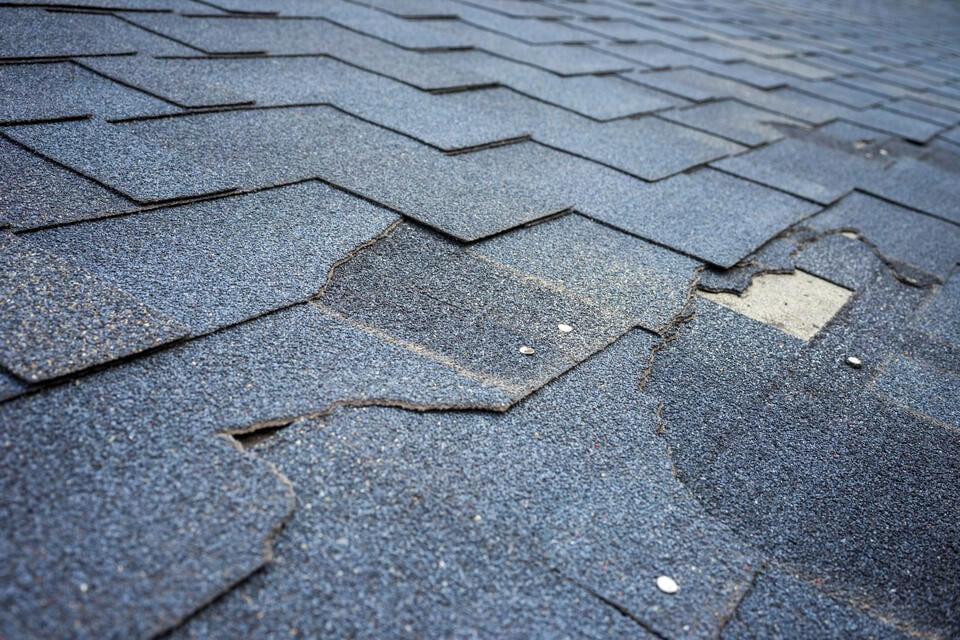 wind damage to roof-close up of cracked and damaged shingles