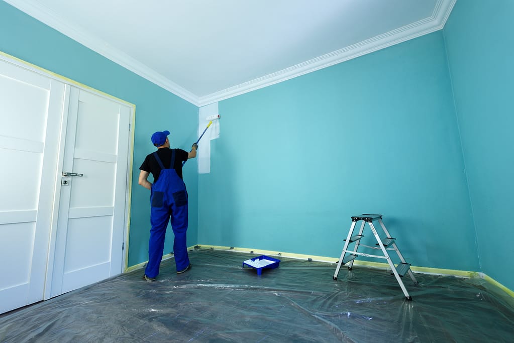 A man is painting the interior of a house white
