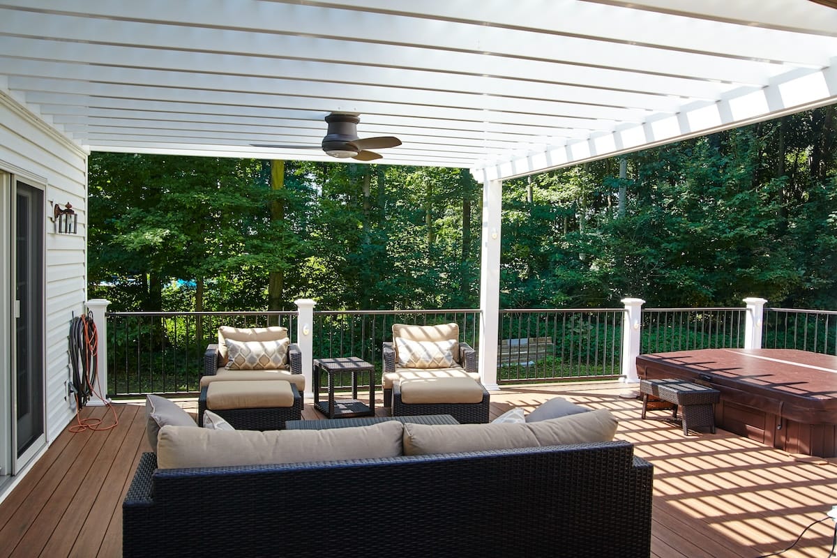 Sunny outdoor residential deck with plush furniture and hot tub, surrounded by lush greenery in Fort Wayne, Indiana, 2015