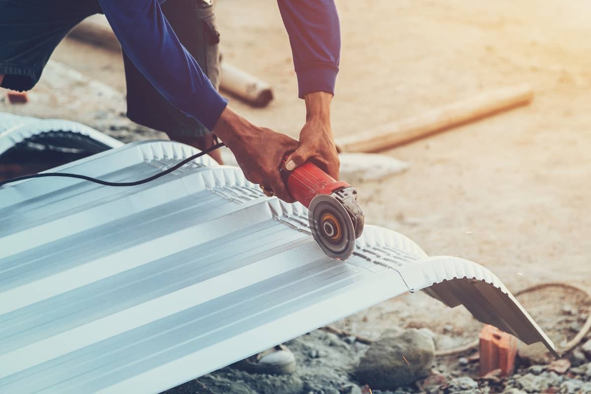 Using a small bladed saw to cut metal roofing material