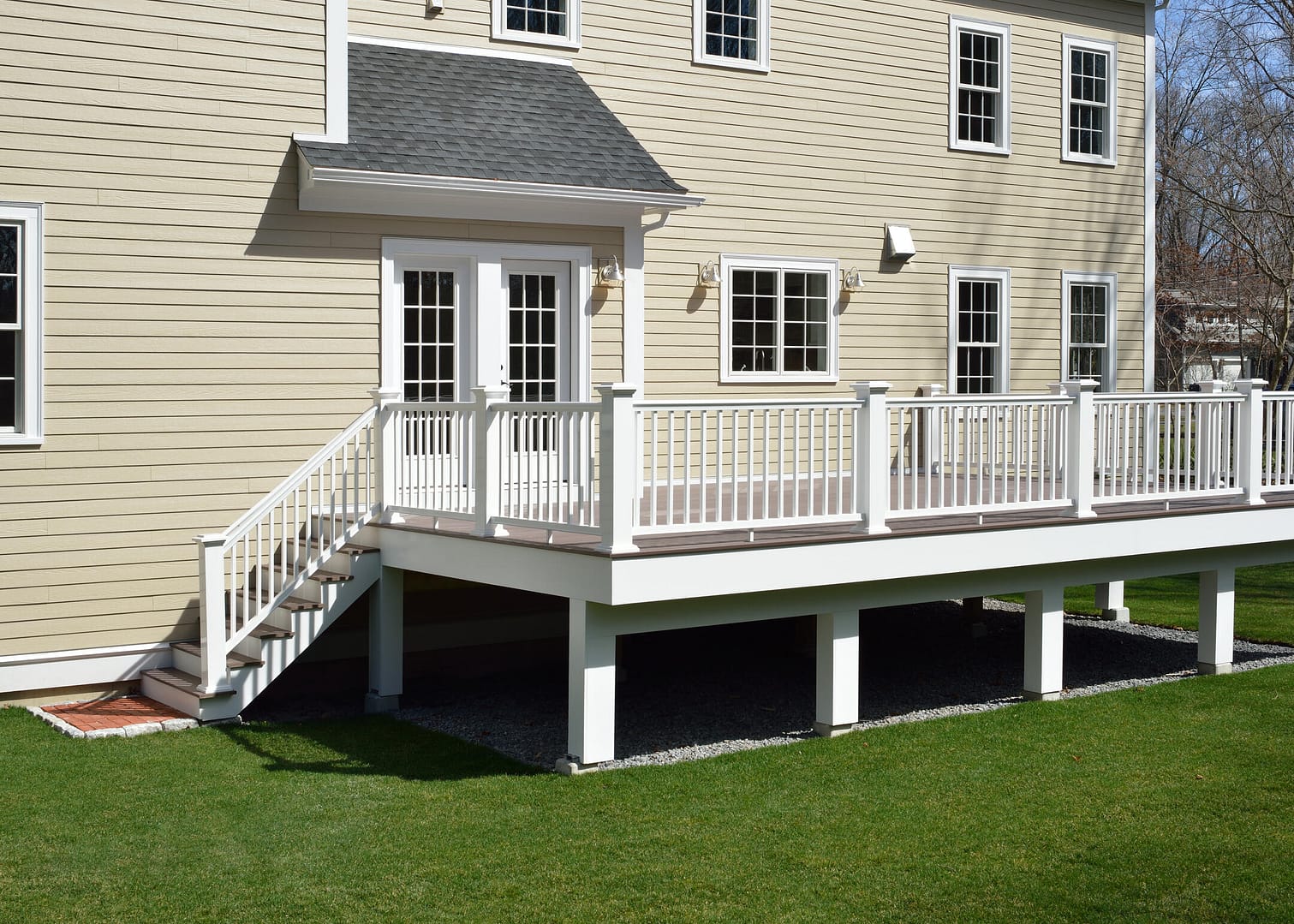 best decking material-cream colored house with a dark stained wood deck and white railing