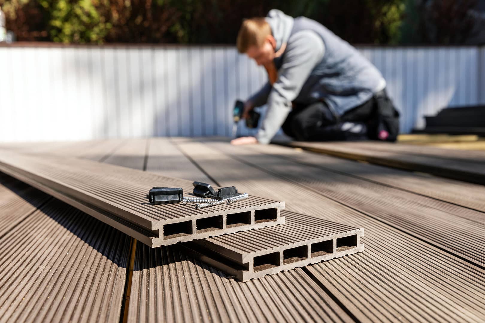 composite wood-person installing decking materials in the background with composite deck slabs in the foreground
