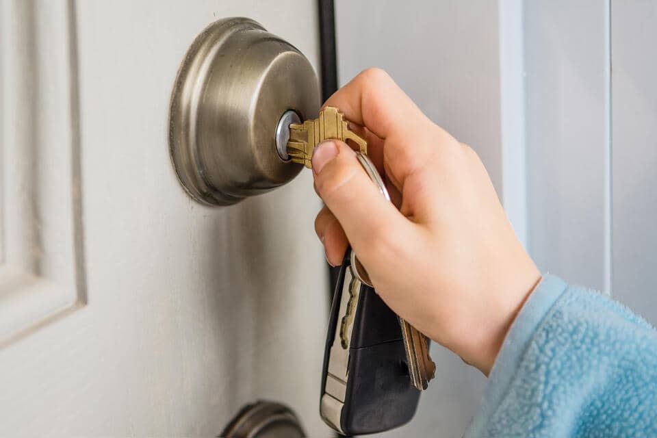 front door styles-woman using keys to lock front door