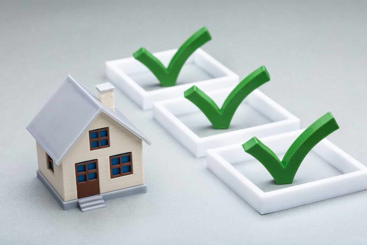 A small model house sits to the left of three check boxes, each with a green check mark. The check boxes are arranged in a horizontal line against a neutral background, symbolizing completed tasks or requirements for homeownership, such as securing Houston roofing services.