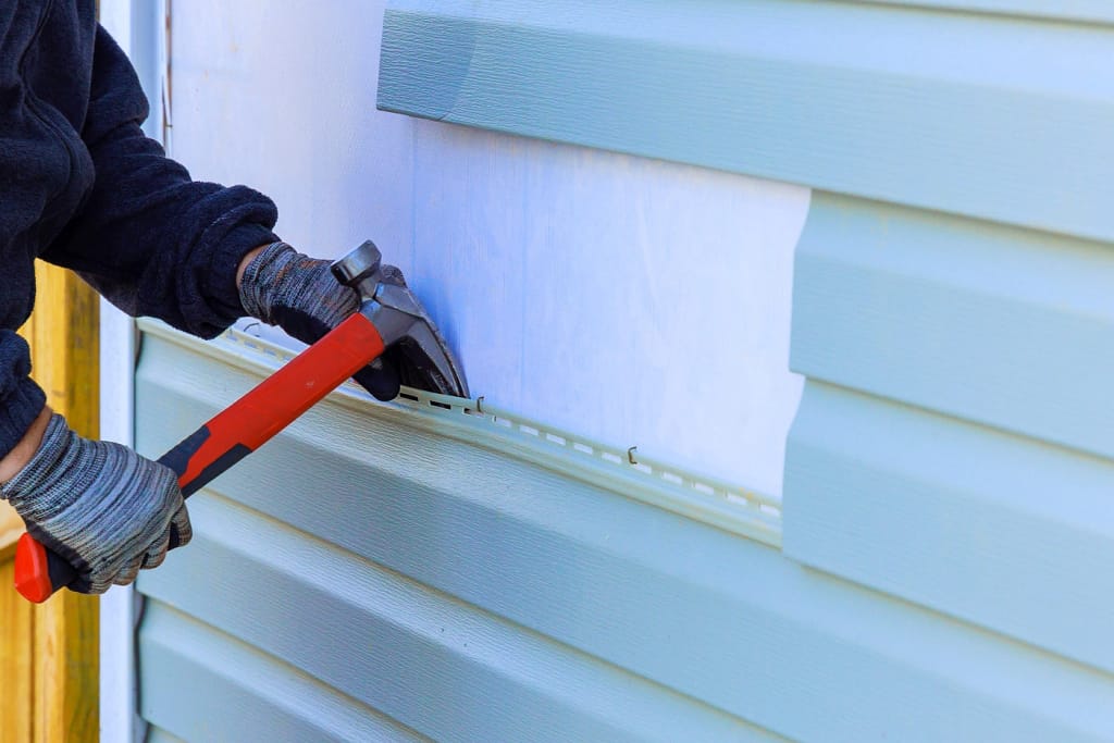 close up of diy siding removal on blue siding house