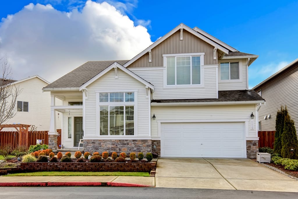 Two story siding house with high column porch and brick trim.