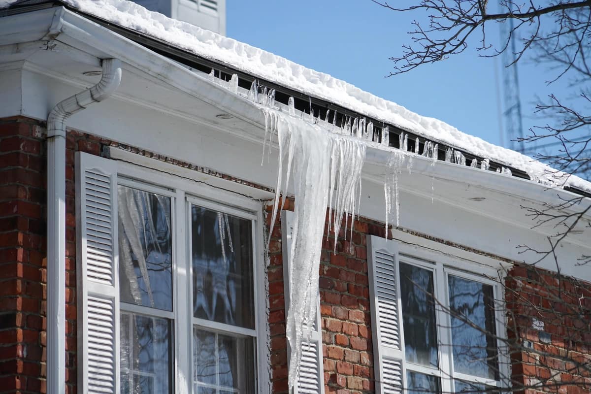close up of ice dams in gutters on brick home in icy winter