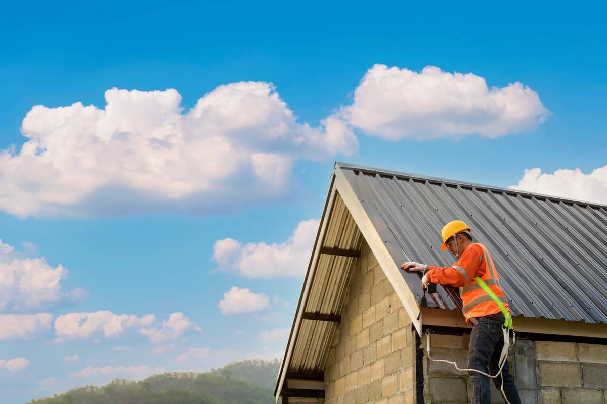 roofer repairing the metal tiles on the house roof
