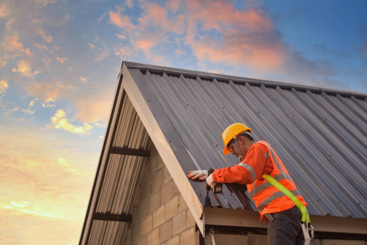 installing a metal roof under sunset