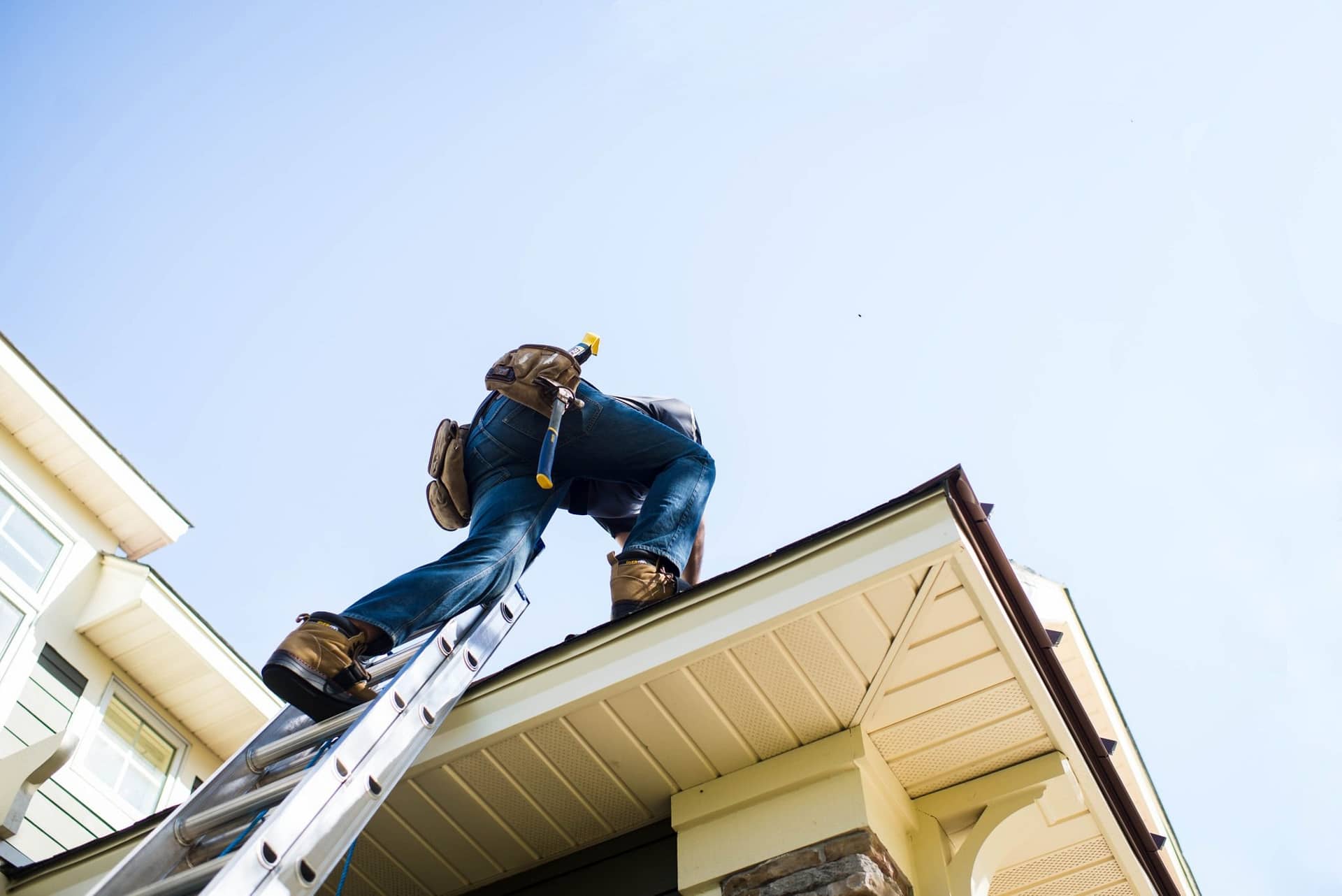 Roof worker getting on roof off ladder