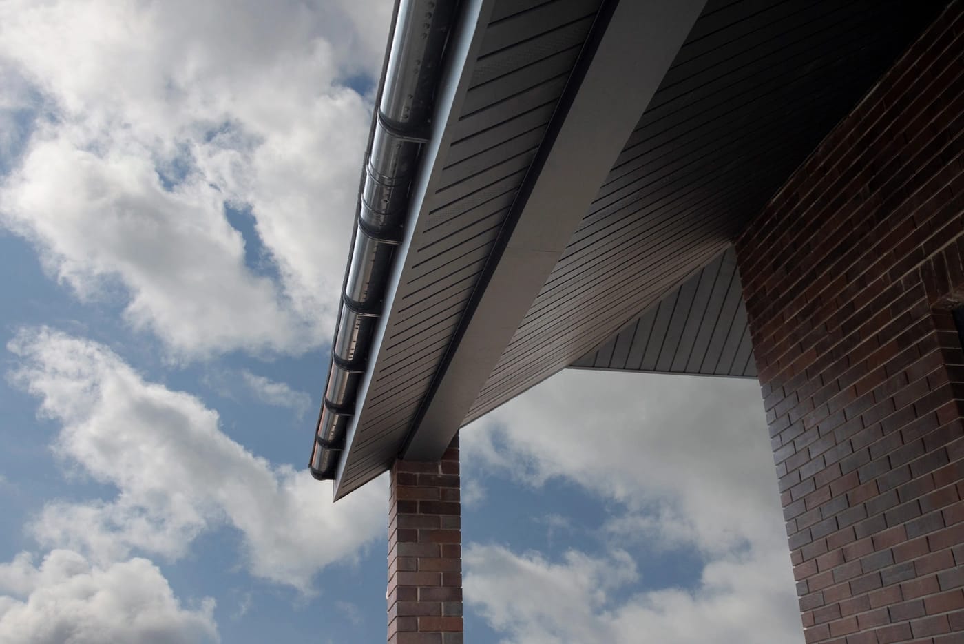 close up of metal gutters and new soffit on a house with blue sky in background