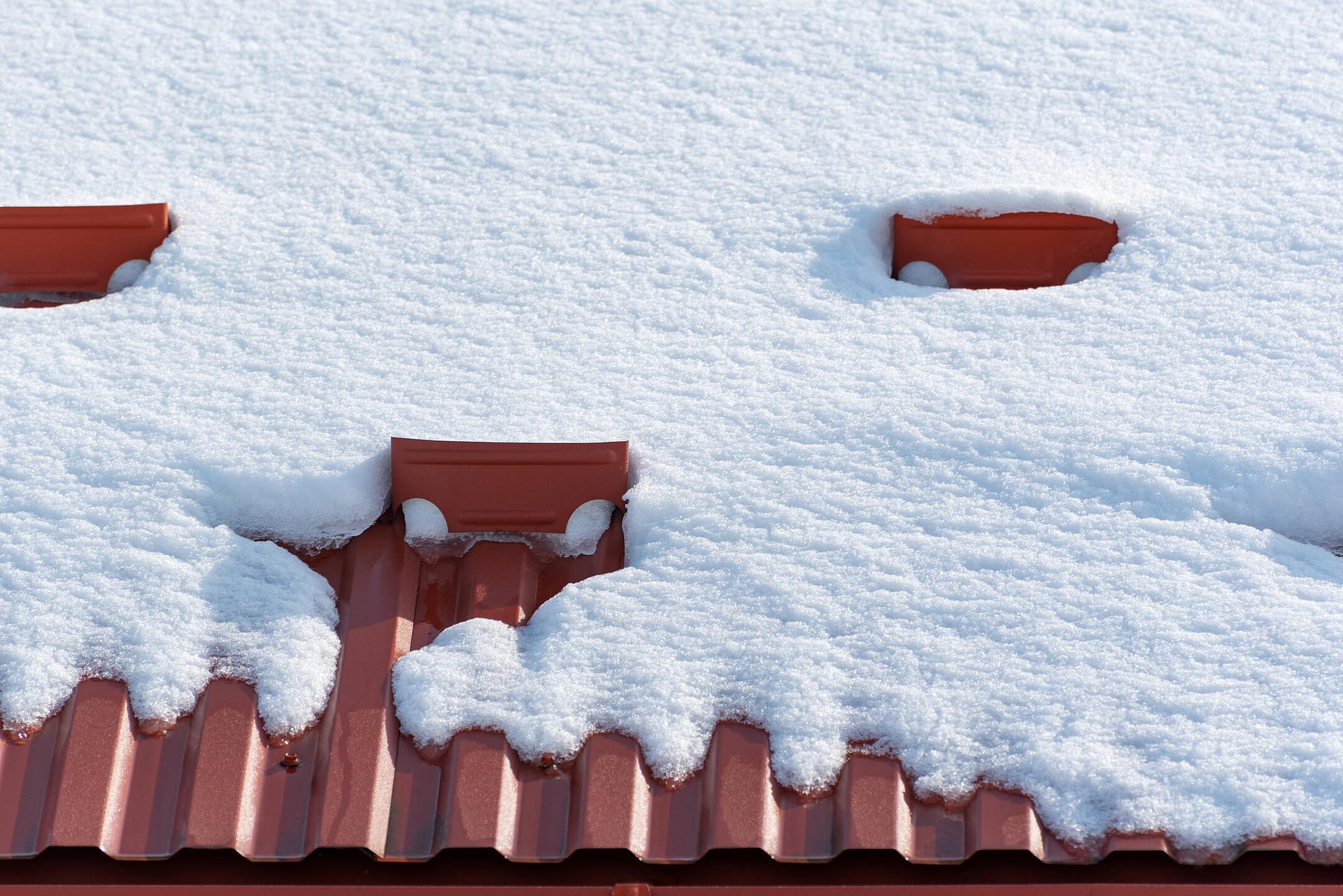 how to install snow guards on metal roof-close up of red corrugated metal roof covered in snow with snow guards