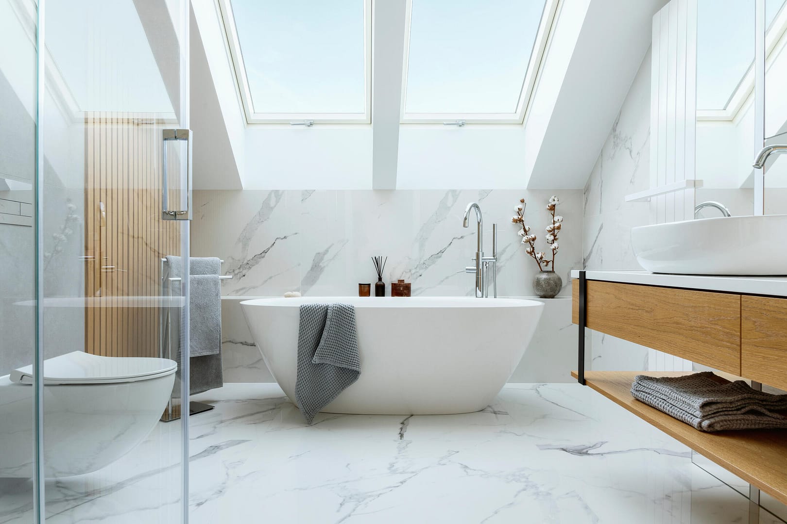 bathroom remodeling-large newly renovated bathroom with standalone tub at the center of the bathroom under skylights and luxury tiling on walls and floor