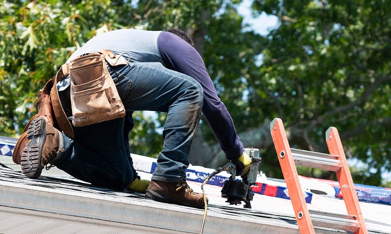 A man drilling on the roof, likely for installation or repair purposes.