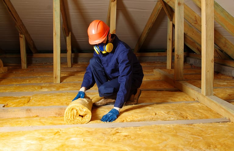 A worker installing insulation in the attic, ensuring proper thermal protection and energy efficiency for the home.