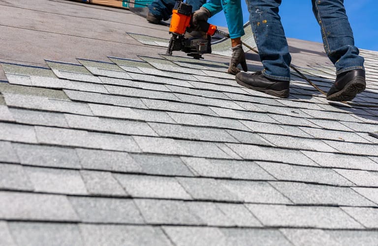 construction worker installing new roof shingles