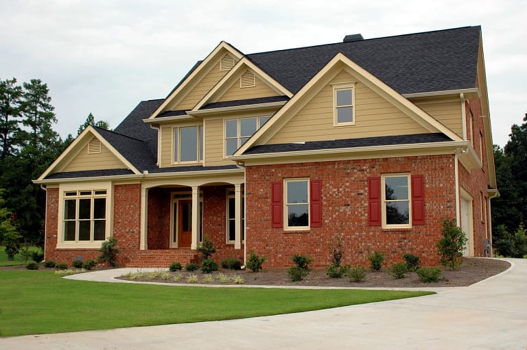 newly built house with stone exterior and dark asphalt roof