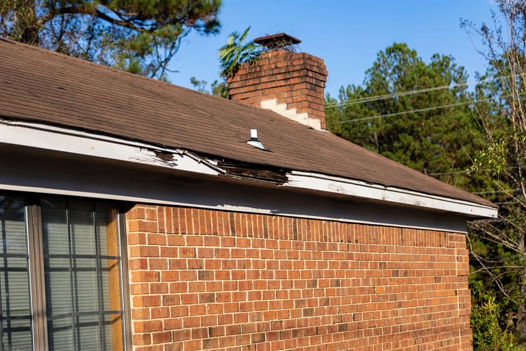 brick house with chimney has damage to fascia and shingles