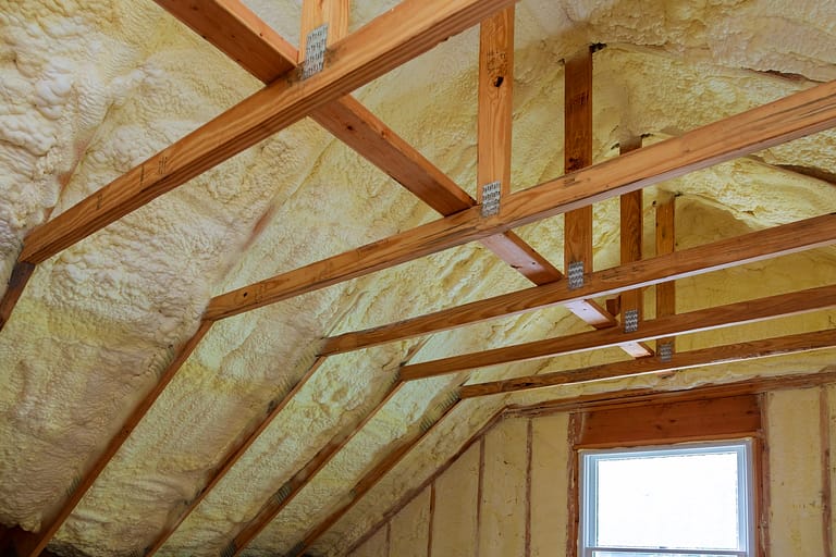 A close view of an attic showing beams, insulation, and structural details of the space.