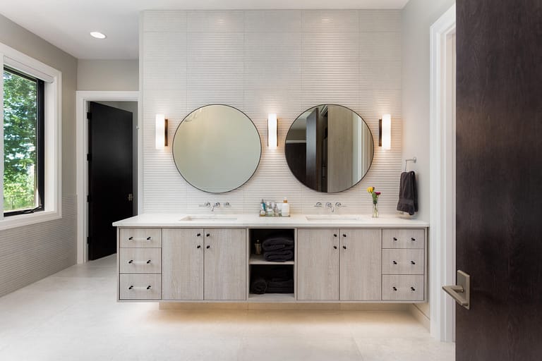 bathroom lighting ideas-modern bathroom with circle mirrors and sconce lights