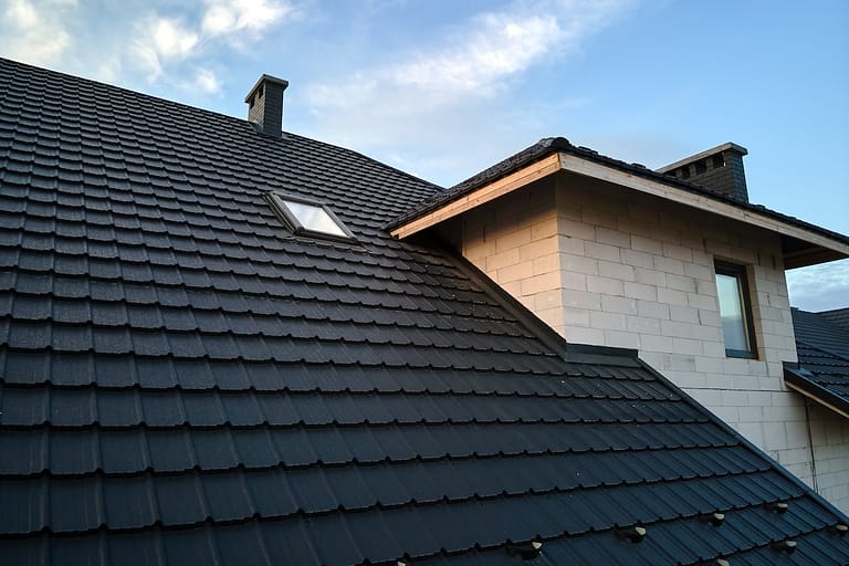 Closeup of house roof top covered with ceramic shingles. Tiled covering of building.