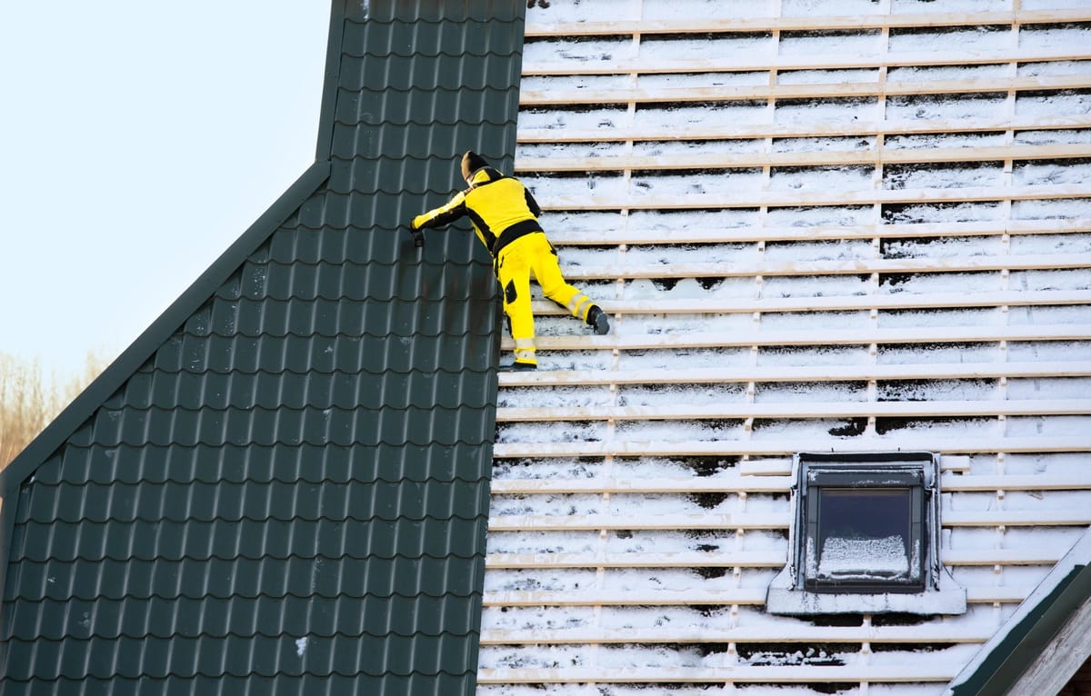 professional reroofing using metal panels on snowy old one