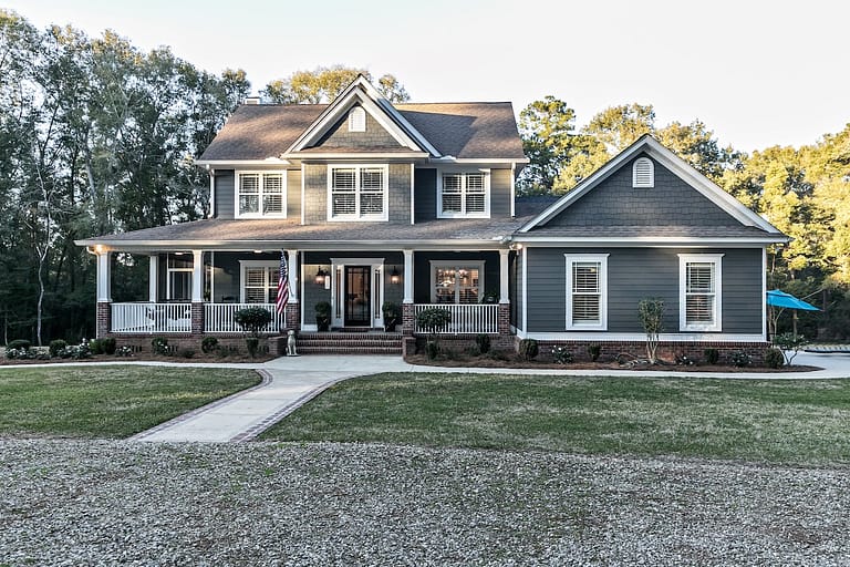 Front view of a large two story blue gray house with wood and vinyl siding