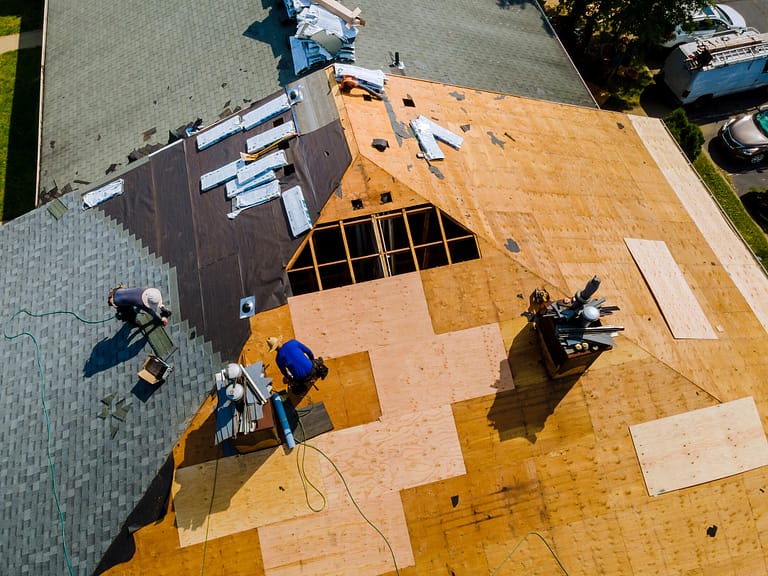 roofing materials list-aerial view of roofing crew replacing a shingle roof