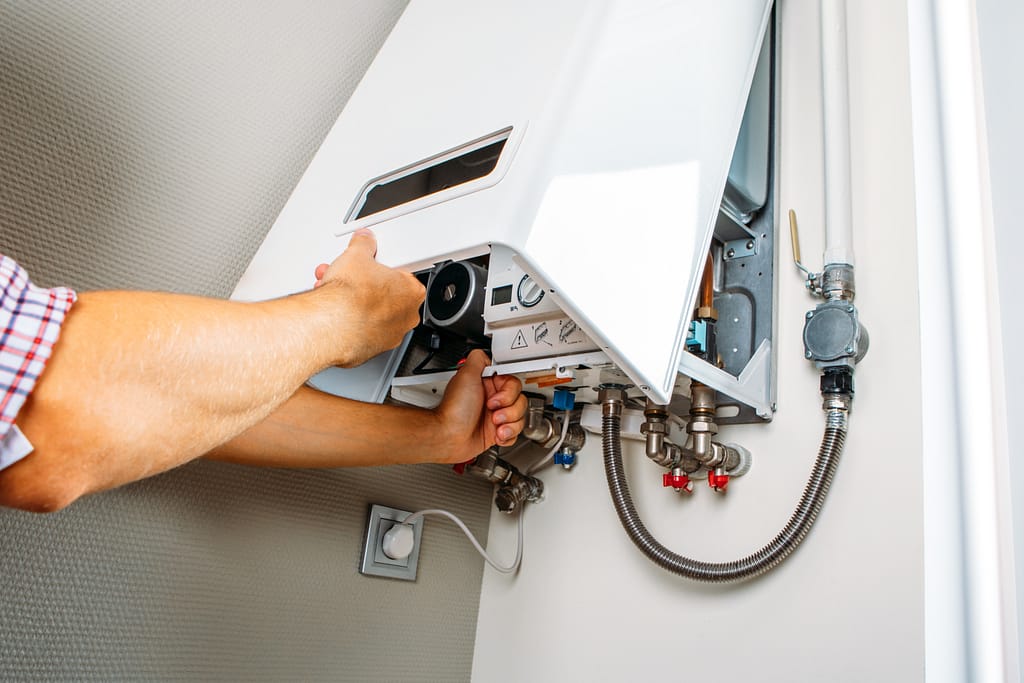 boiler Plumber attaches Trying To Fix the Problem with the Residential Heating Equipment. Repair of a gas boiler