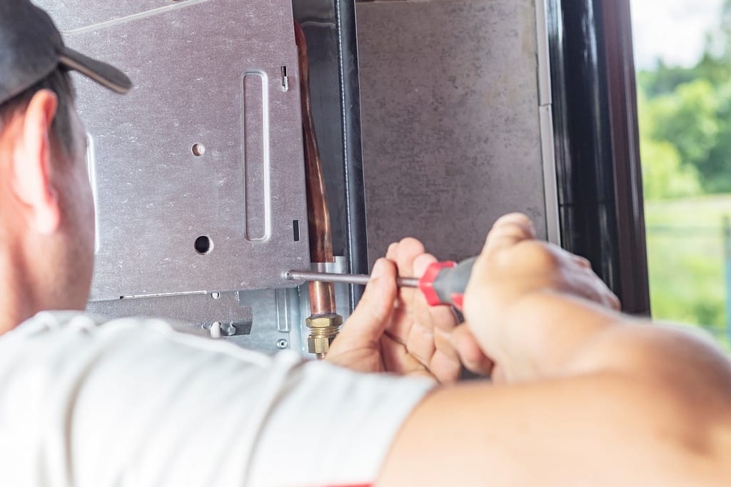 gas furnace installation The master sets up a gas boiler, which weighs on the wall. The front dashboard is open. The removal and installation of gas nozzles for gas supply.