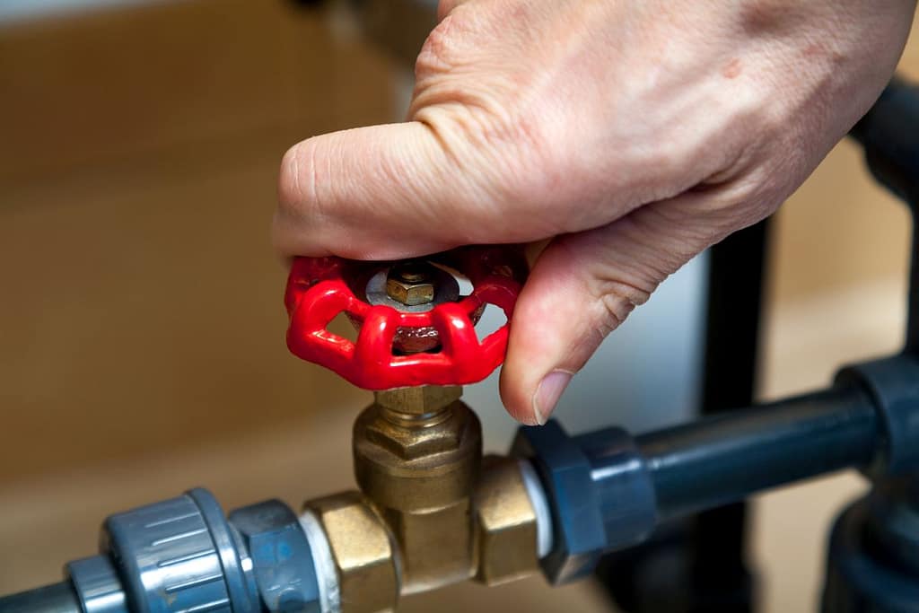 backflow testing man's hand spins water valve close up