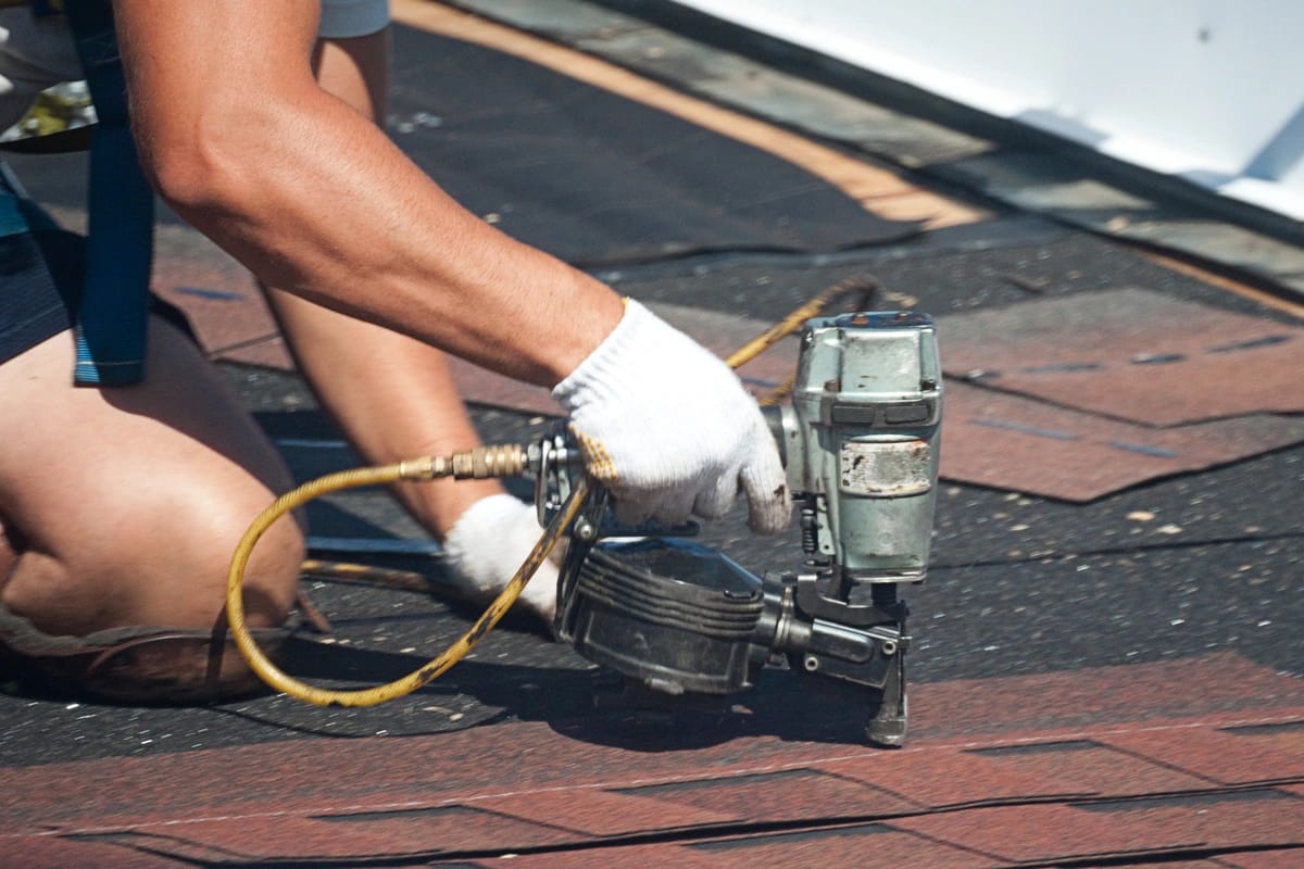 close up of contractor reroofing using nail gun