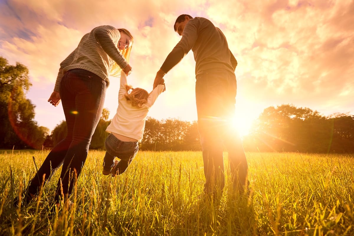 Two parents with their child in a field