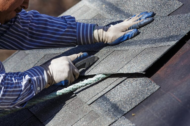 man installing impact resistant shingles on a new roof