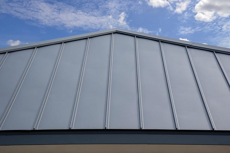 standing seam metal roof-close up of gray standing seam roofing near the peak of a house roof