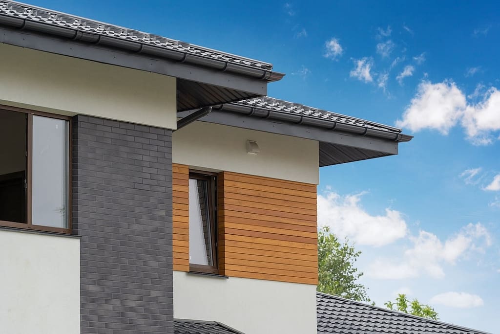 Outside photo of beautiful and comfort new house with few apartment and flat room large windows and stone wooden elements on white wall against beautiful sky