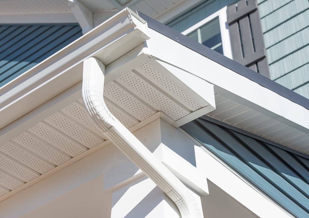 Colonial white gutter guard system, fascia, drip edge, soffit providing ventilation to the attic, with pacific blue vinyl horizontal siding at a luxury American single family home neighborhood USA