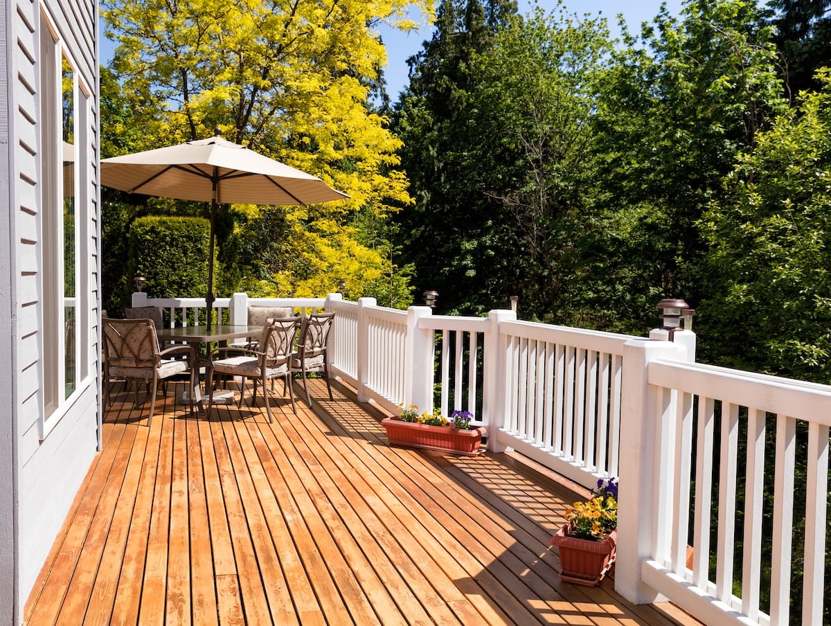 Home outdoor cedar deck with blooming trees and blue sky in background