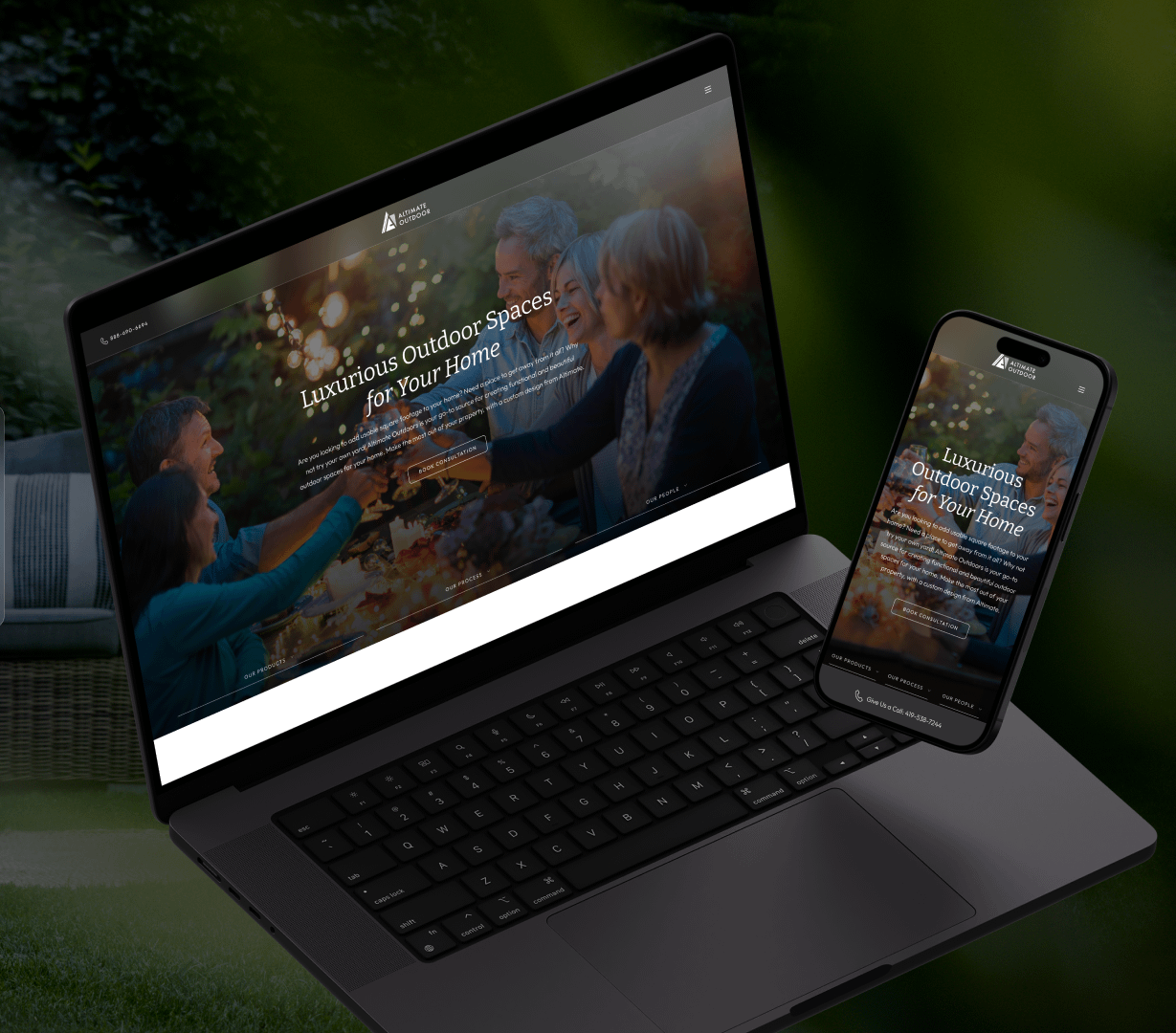 On display, a laptop and smartphone feature a website with the headline "Luxurious Outdoor Spaces for Your Home," expertly designed by Cincinnati web specialists. In the background, individuals savor an outdoor meal at a table beautifully decorated with lush greenery.