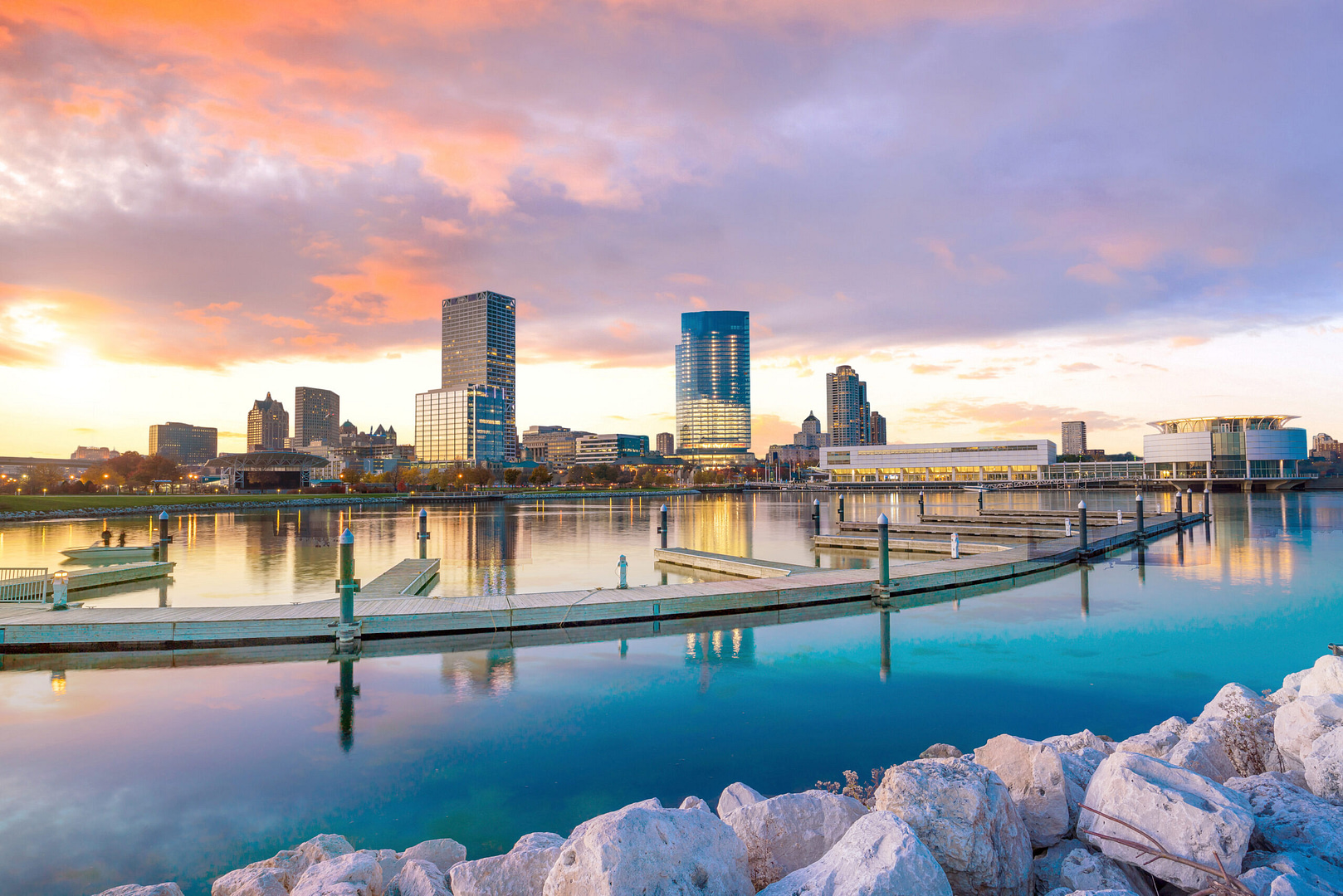 Experience Milwaukee's SEO innovation reflected in its skyline, where modern high-rises illuminate the serene waters of a quiet marina. The vibrant sunset casts an orange, pink, and blue glow, symbolizing the city's dynamic growth in digital marketing excellence.