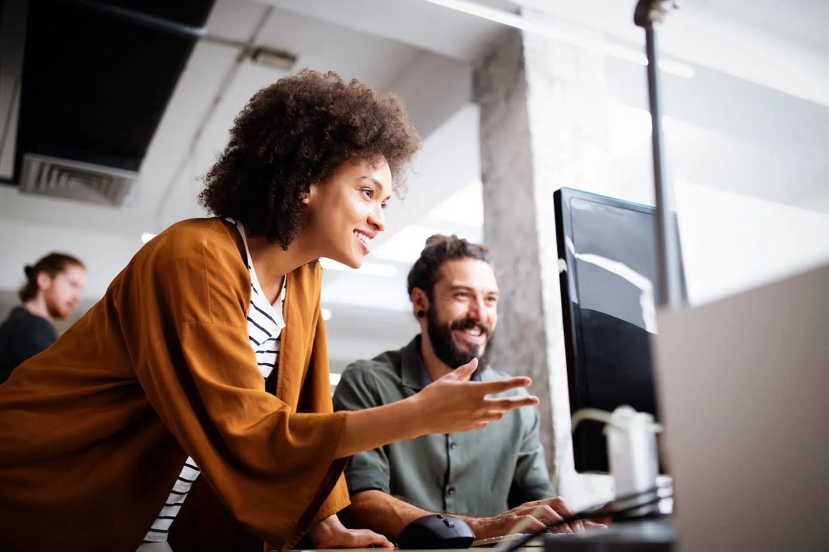 In a contemporary office environment, two colleagues engage enthusiastically over a computer screen, exploring effective strategies for Phoenix SEO.