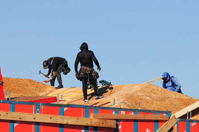 Construction crew working on a wood roof of a home
