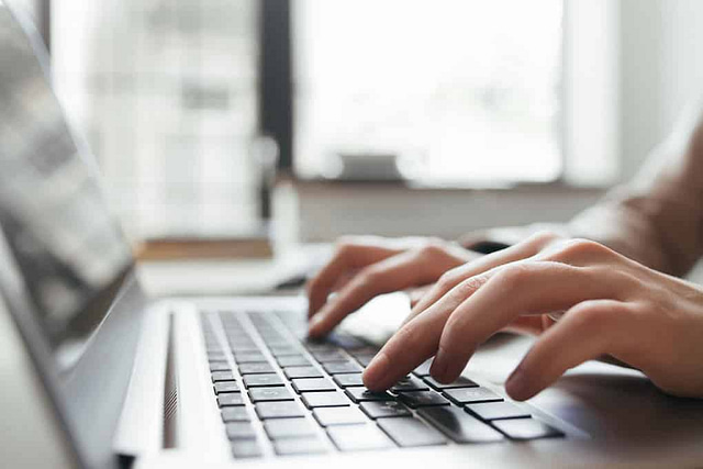 hands typing on a laptop performing content marketing