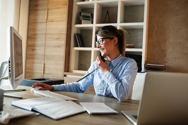 female roofing office manager talking on the phone and working on her computer