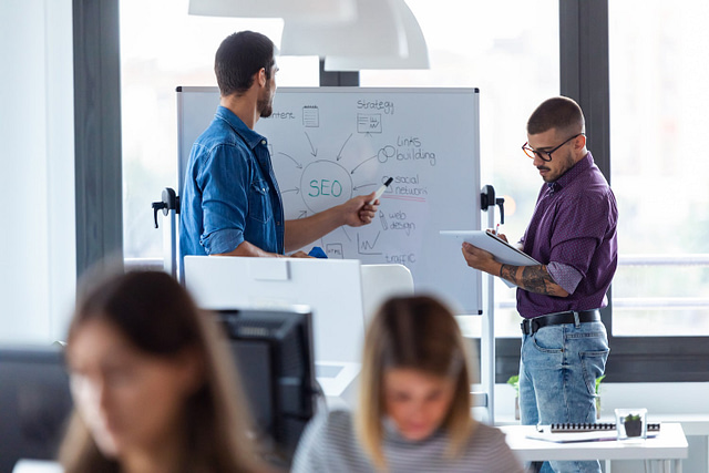 two men at white board discussing roofing seo agency hiring tips